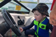 Little boy thinks he is driving the boat.