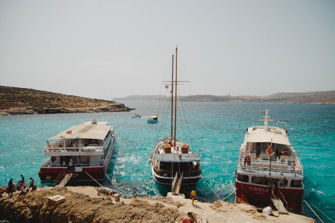 Three boats moored next to one another in a blue-water harbour