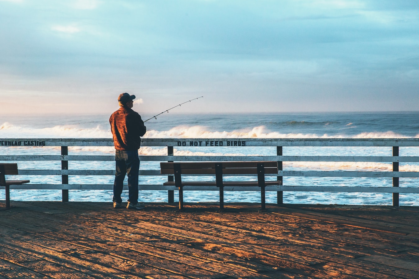 Man standing alone on a pier fishing