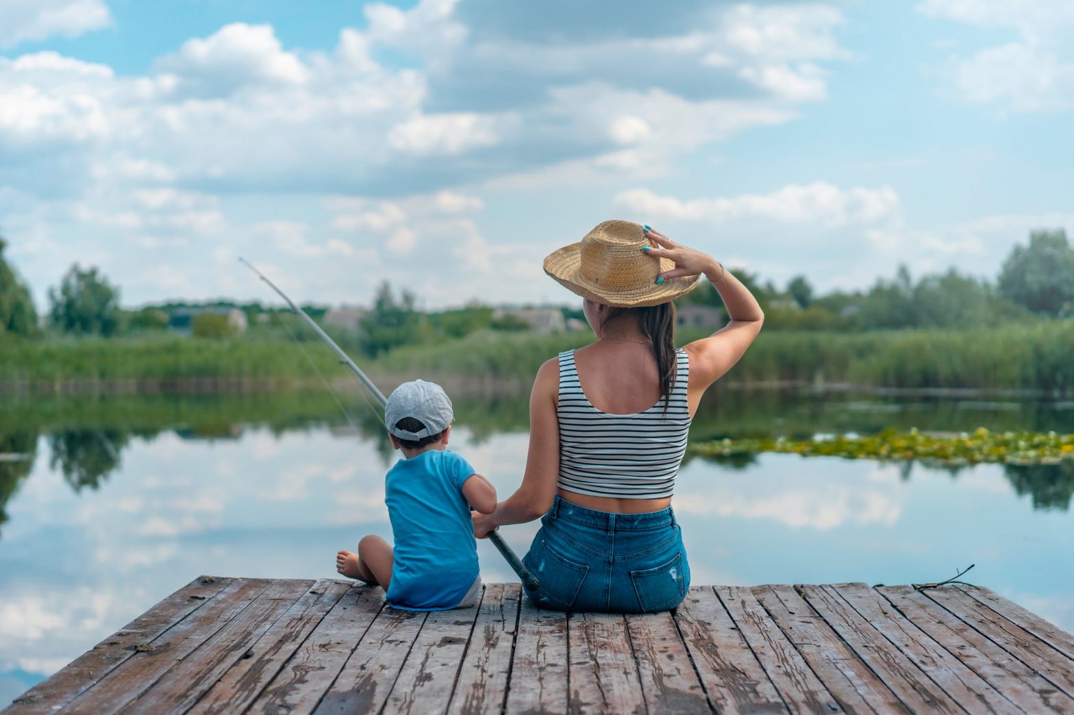 Woman and young son sitting on a wooden dock, fishing