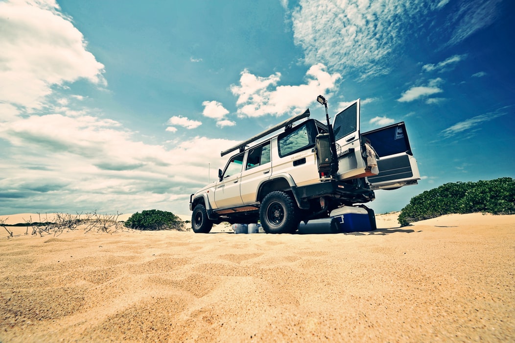 White four-wheel-drive parked on the sand with rear doors open to be packed