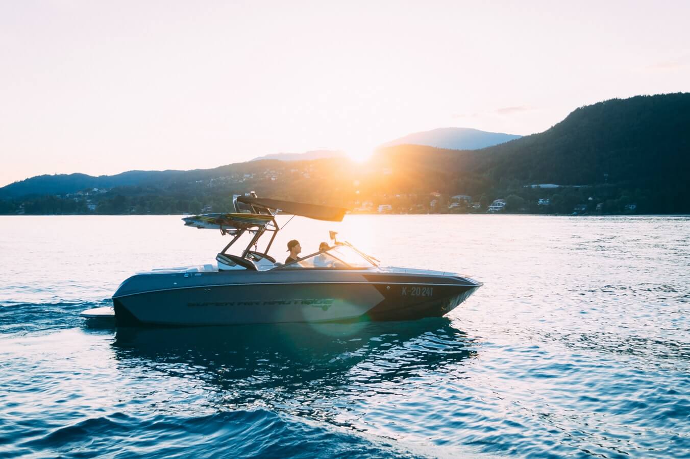 Small boat travelling across the water at sunset