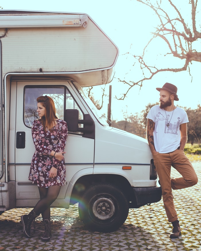 Young couple leaning up against their caravan