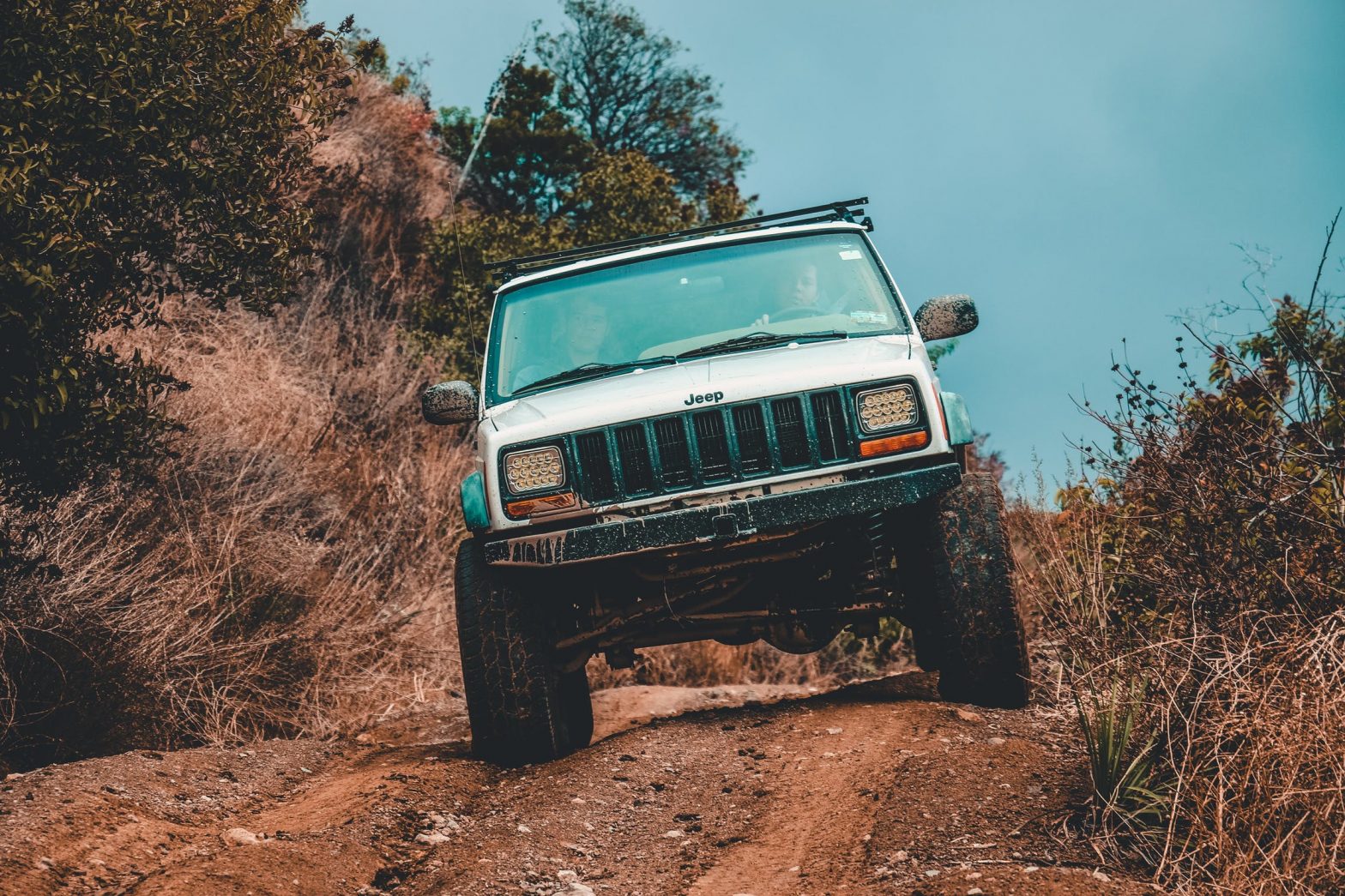 White jeep travelling downhill on a dirt off-road track