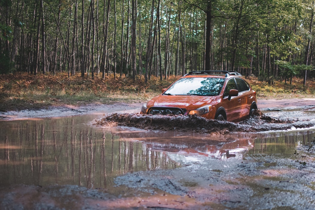 Red four-wheel-drive entering a water crosing