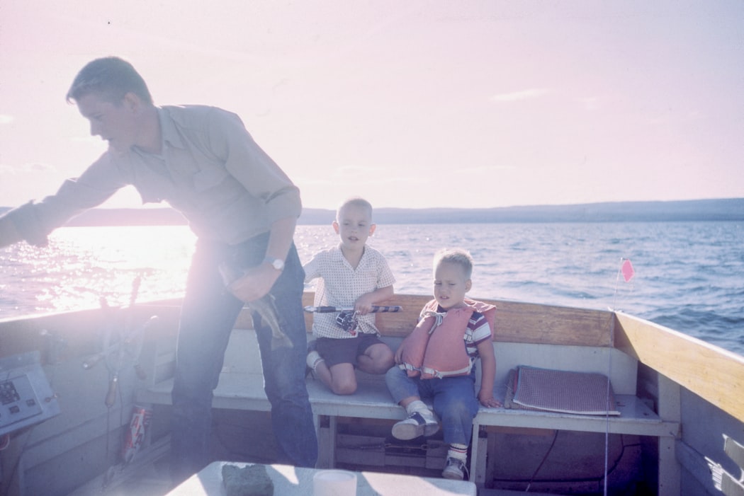 Father fishing with his children on a small boat at sunset