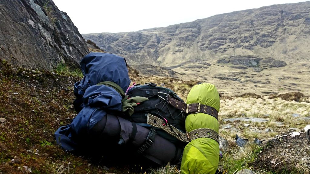 Green and black camping gear sat on a grassy hill