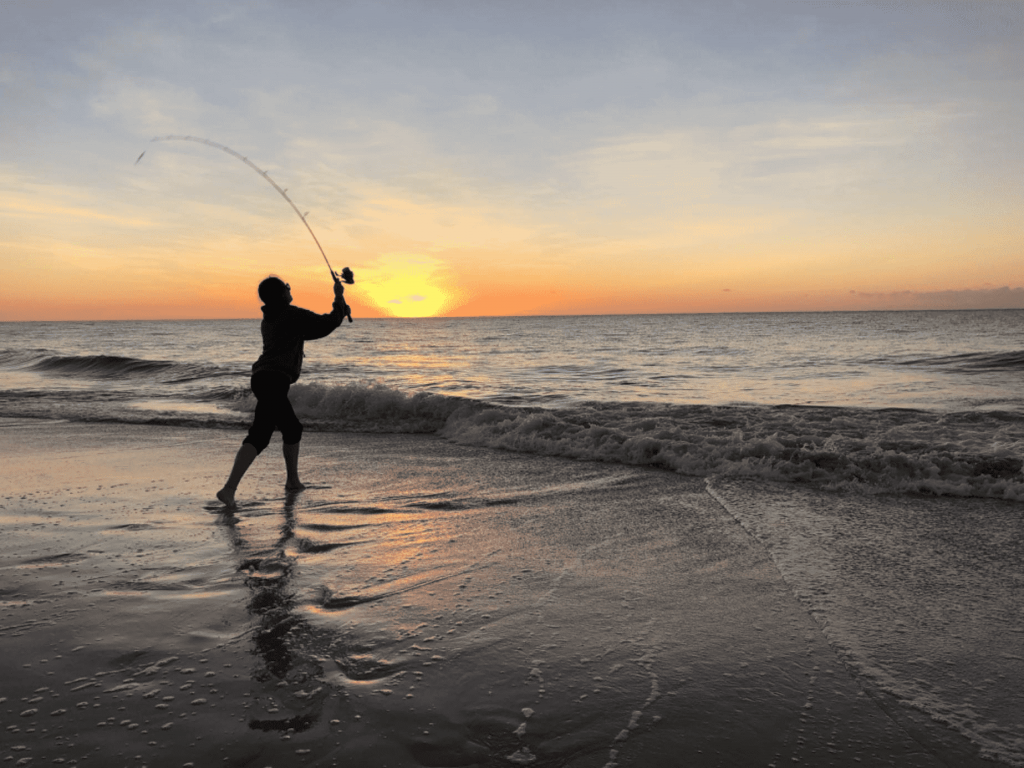 Silhouette of a person fishing at sunset