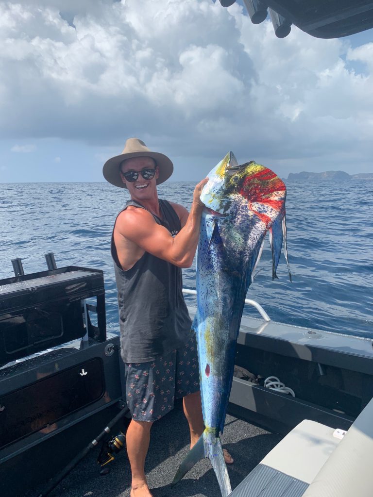 Josh Hook holding a large, fresh caught dophin fish on his boat at Old Bar