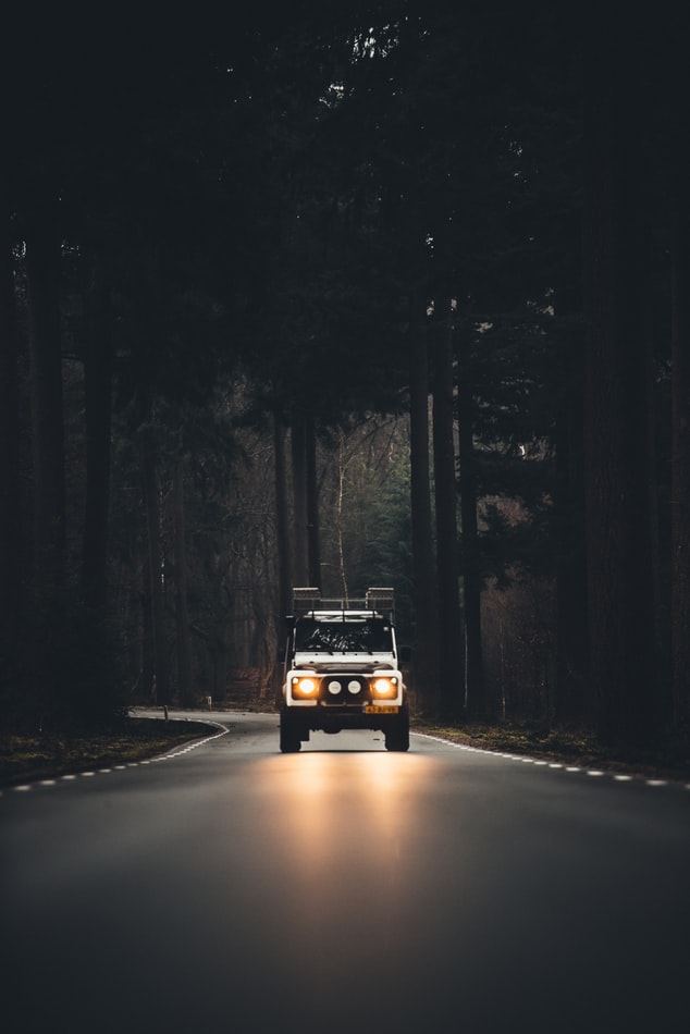 White 4wd shining bright lights on a dark, deserted road