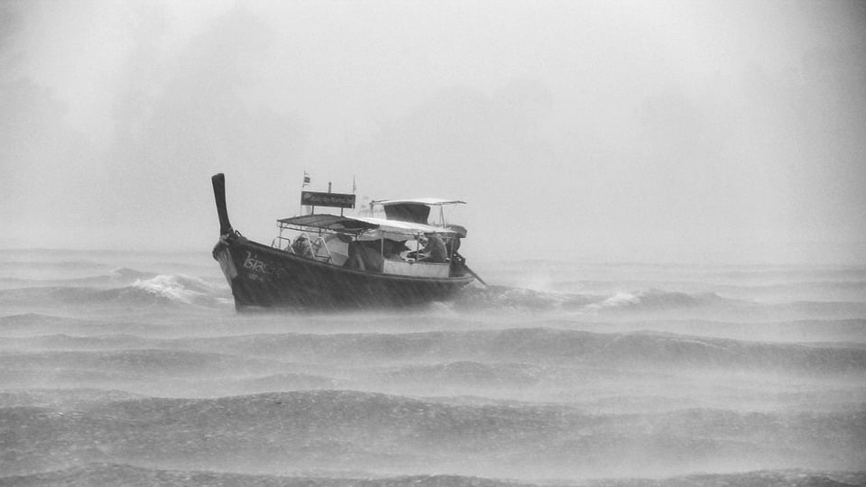 Black and white image of a boat on the ocean in a storm
