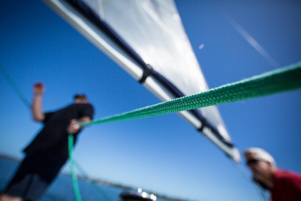 Man learning to sail holding green rope