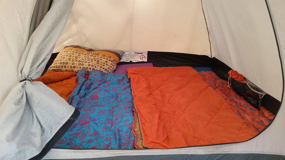 Tent lined with colourful sleeping mats and sleeping bags