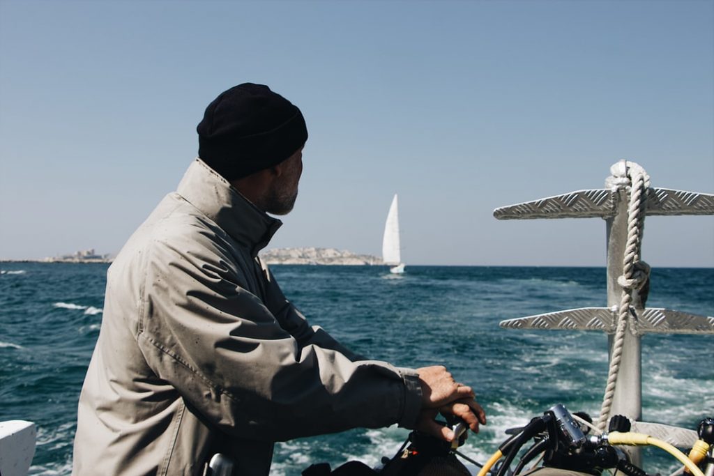 Man in grey weatherproof jacket on the back of a boat